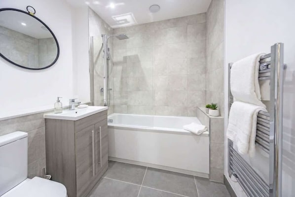 A modern bathroom with a bathtub, a shower, and a toilet. - Central 2BR Ashford Flat with Fast Wi-Fi & Parking (Ashford)