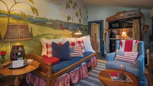 A cozy room with a bed, a blue armchair, and a table with a lamp.