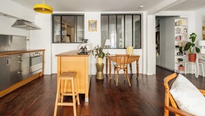 Eine moderne Küche mit Holzboden, einem Essbereich mit Tisch und Stühlen sowie einer sichtbaren Treppe zu einer weiteren Ebene.