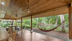 A covered outdoor dining area with a hammock, wooden ceiling, and a view of a lush garden. - Spacious 3-Bedroom Coastal Home with Shared Pool, Outdoor Living & Steps to Playa Potrero (Potrero)