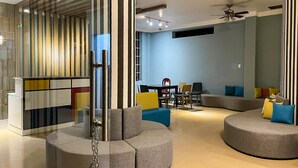 A modern living room with a sectional sofa, a dining table, and a glass partition with vertical stripes.