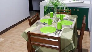 A dining area with a table set for four, green tablecloth, wooden chairs, and a potted plant on the table. - Cozy, Safe, and Secure Two-Bedroom Apartment Unit (San Carlos City)