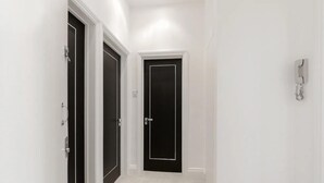 A narrow hallway with white walls and black doors. - Modern 2 bed Apartment in Notting Hill (London)