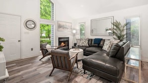 Un salon moderne avec une cheminée, un canapé en cuir et un coin repas.