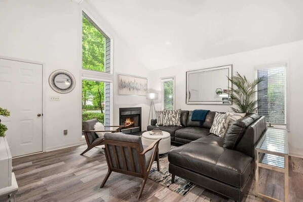 A modern living room with a fireplace, leather sofa, and a dining area.