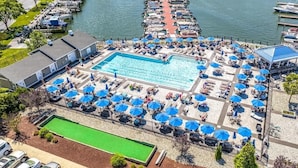 Un espace piscine doté de plusieurs zones aménagées pour prendre des bains de soleil et d’une piscine centrale.