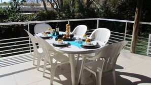 Une table ronde avec des chaises blanches, une nappe bleue et des assiettes décorées de motifs jaunes.