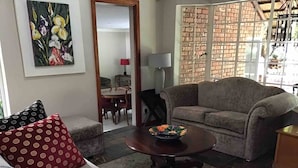 Un salon comprenant un canapé, une table basse, un coin repas avec des chaises et un mur en briques.