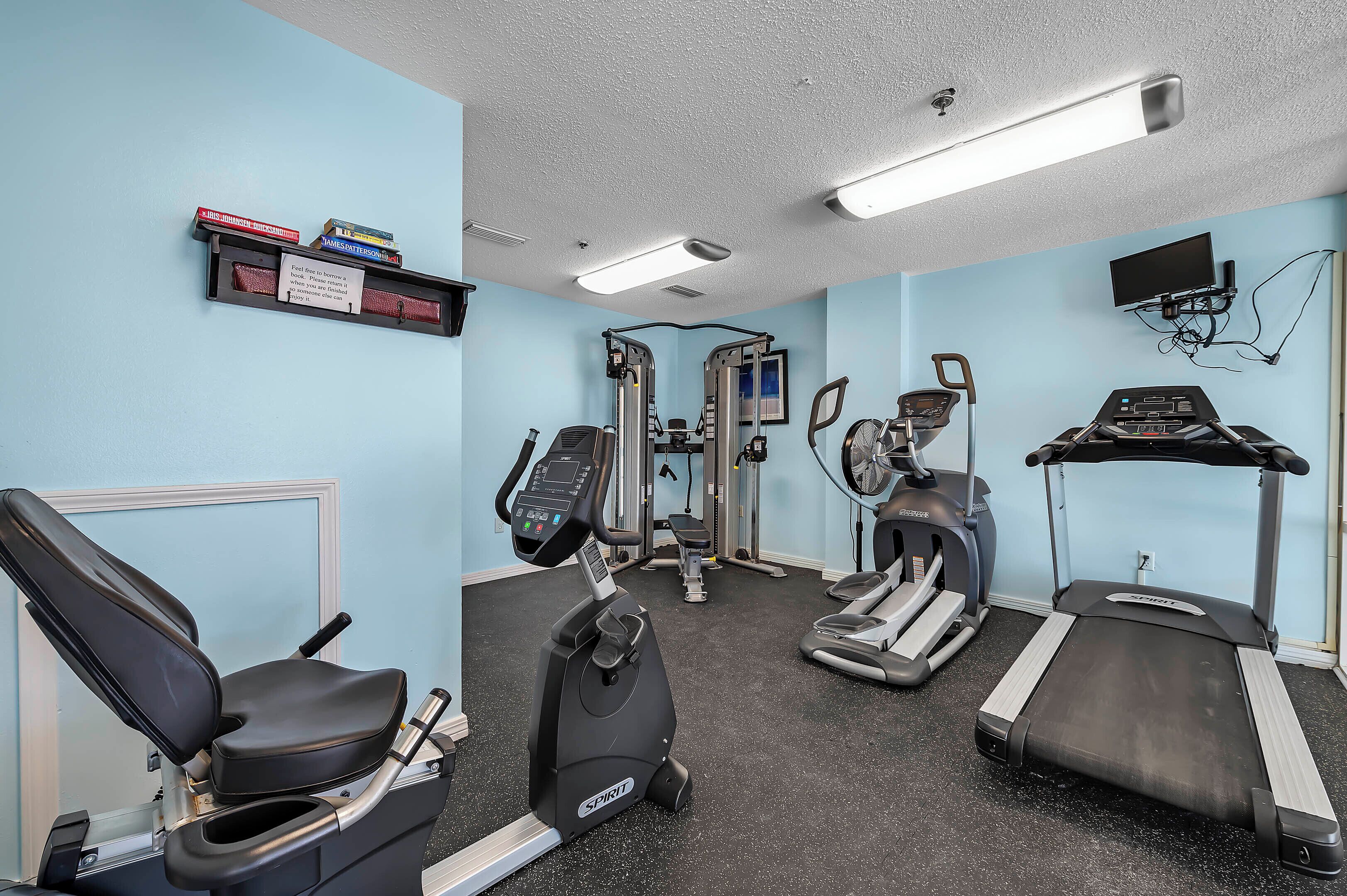 Une salle de sport équipée de tapis de course, d’un appareil elliptique et de machines de musculation.