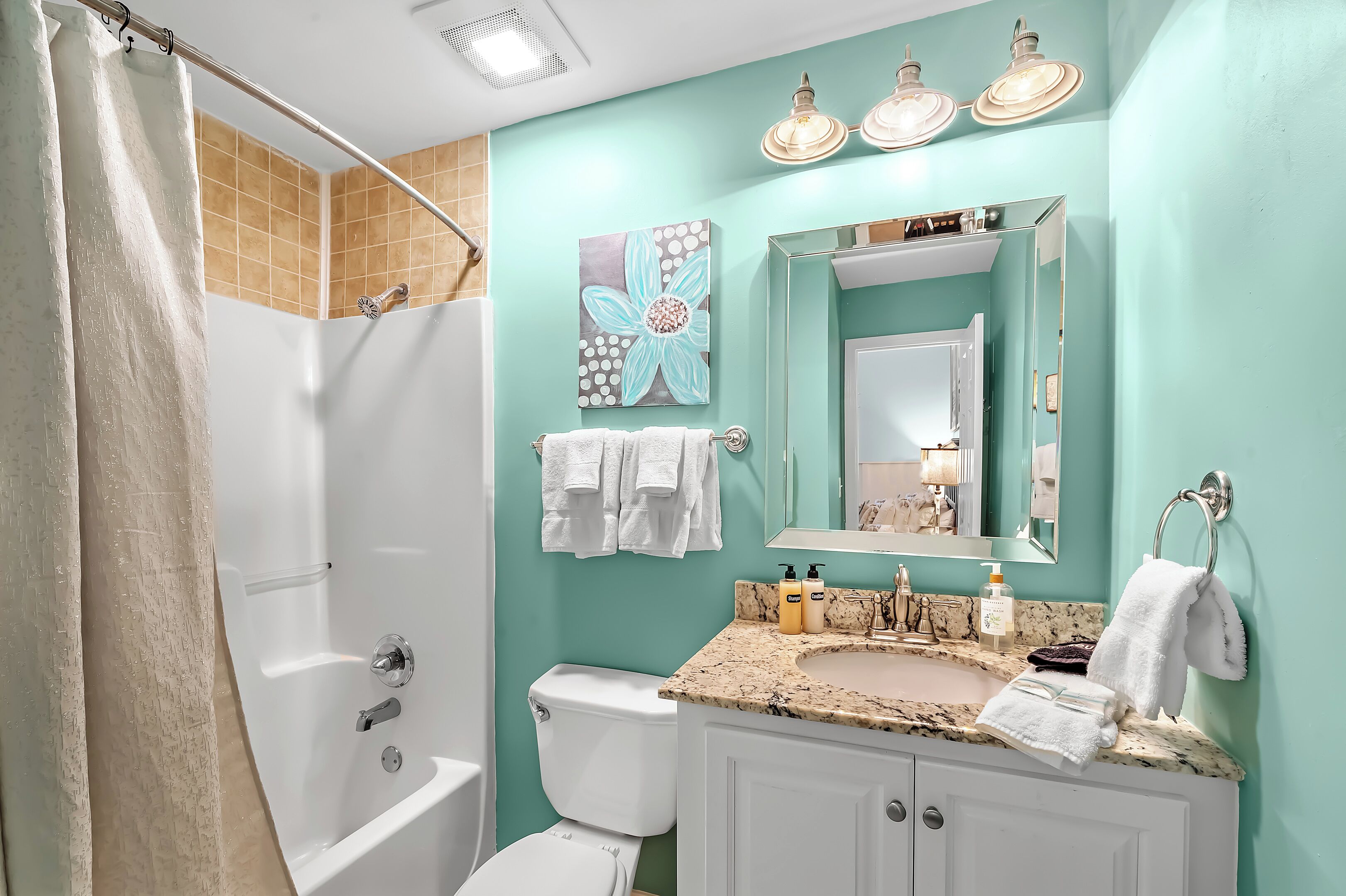 A bathroom with a bathtub, toilet, sink, and a mirror.