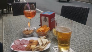 Una mesa con un plato de comida, una cerveza en un vaso y una caja de bocadillos.