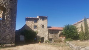Un edificio de piedra con una torre, un arco de entrada y plantas en macetas.