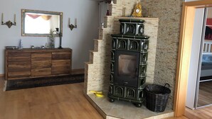 Una sala de estar con un aparador de madera, una chimenea verde y un espejo en la pared.
