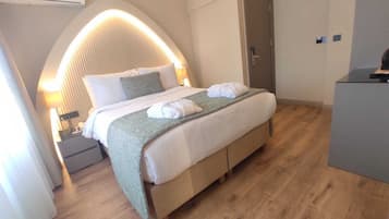 Una habitación de hotel moderna con una cama grande, un escritorio, una silla y un equipo de aire acondicionado.