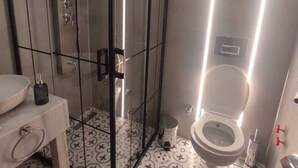 Une salle de bain moderne dotée d’une douche à parois de verre, de toilettes et d’un lavabo avec un revêtement mural décoratif en carreaux.