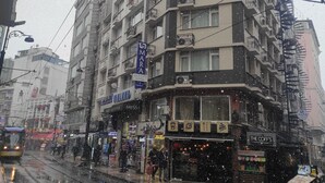 Un immeuble à plusieurs étages doté de balcons, une enseigne indiquant « MARA Old City Hotel », et une devanture de magasin nommée « The Coff's ».