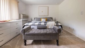 A bedroom with a bed, bedside tables, a dresser, and a window with blinds. - Charming 1BR Condo with Patio, Near The Lake Geneva (Lake Geneva)
