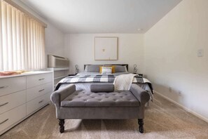 Un dormitorio con cama, mesitas de noche, cómoda y ventana con persianas.