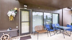 A covered patio with a table and chairs, a door, and a decorative wreath. - Charming 1BR Condo with Patio, Near The Lake Geneva (Lake Geneva)