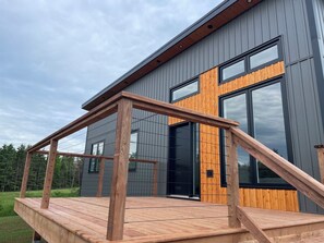 Un bâtiment moderne doté d’une terrasse en bois et de grandes fenêtres.