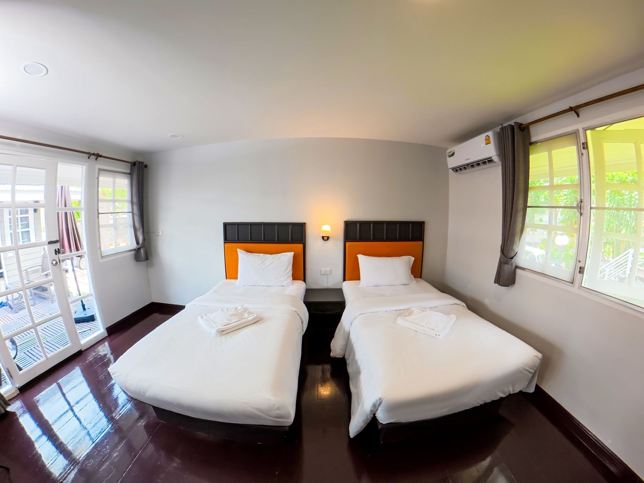 Habitación de hotel con dos camas, balcón y vista a la vegetación.