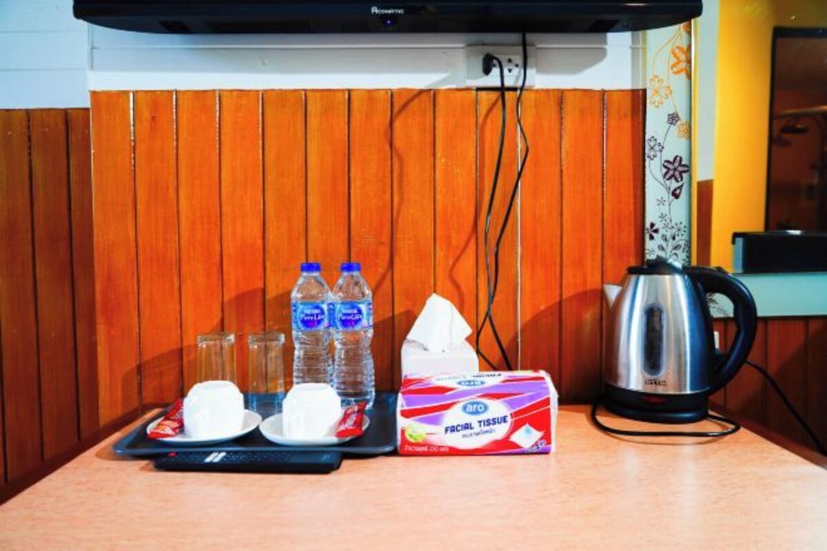 A kitchen area with a kettle, water bottles, a tissue box, and a microwave.