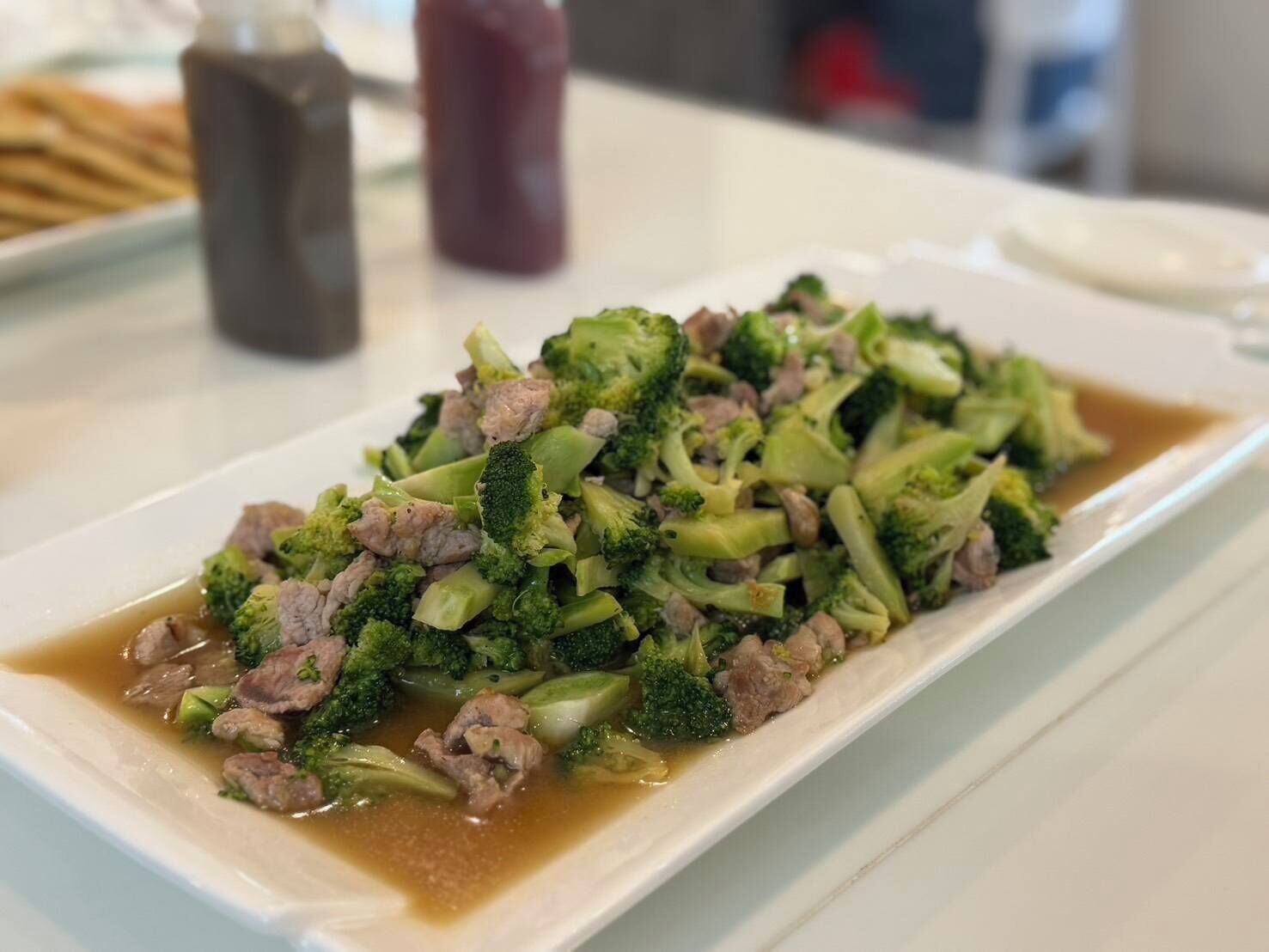 A dish of beef and broccoli in a white rectangular plate.