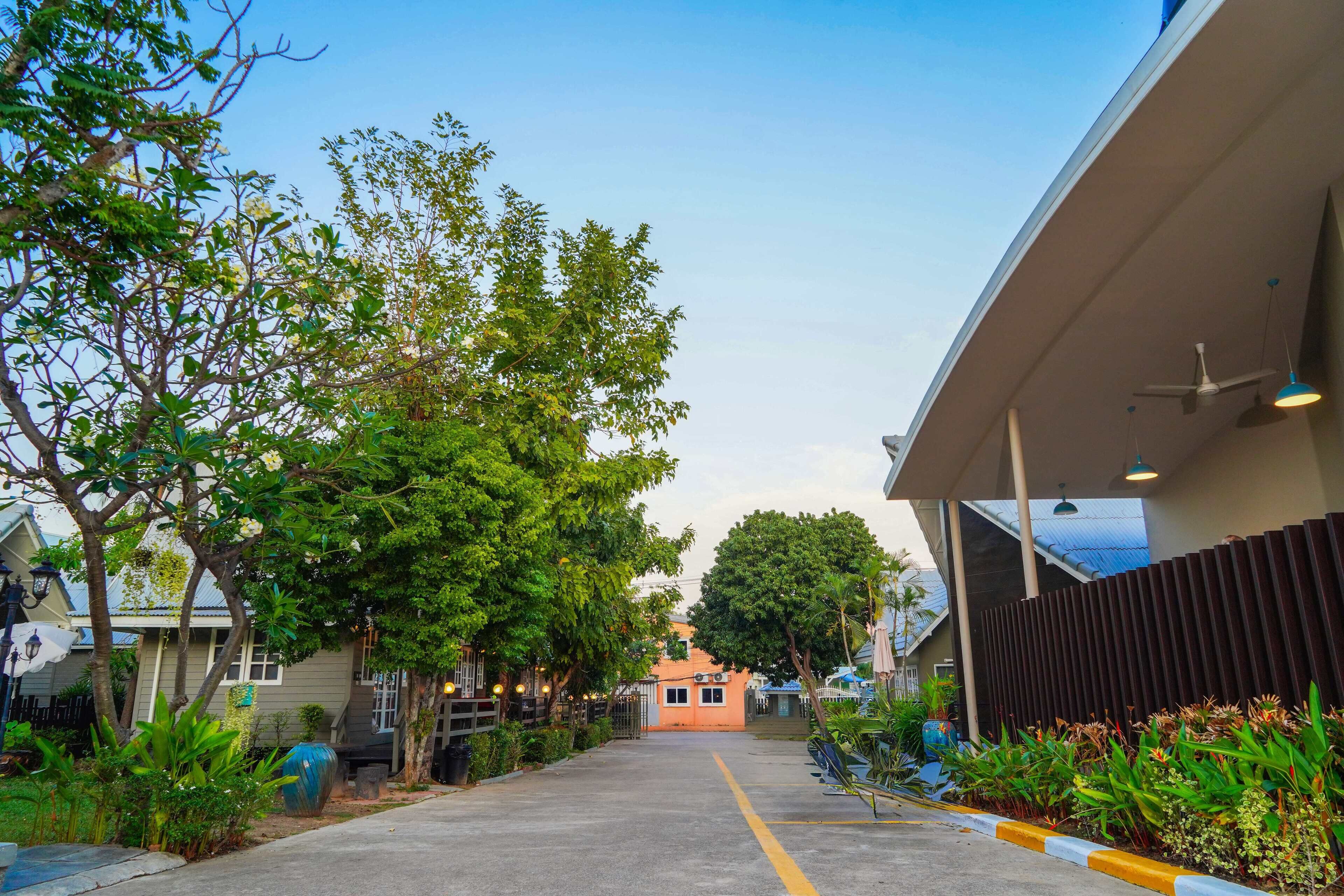 A pathway leading to a building with a covered area and a fence on one side.