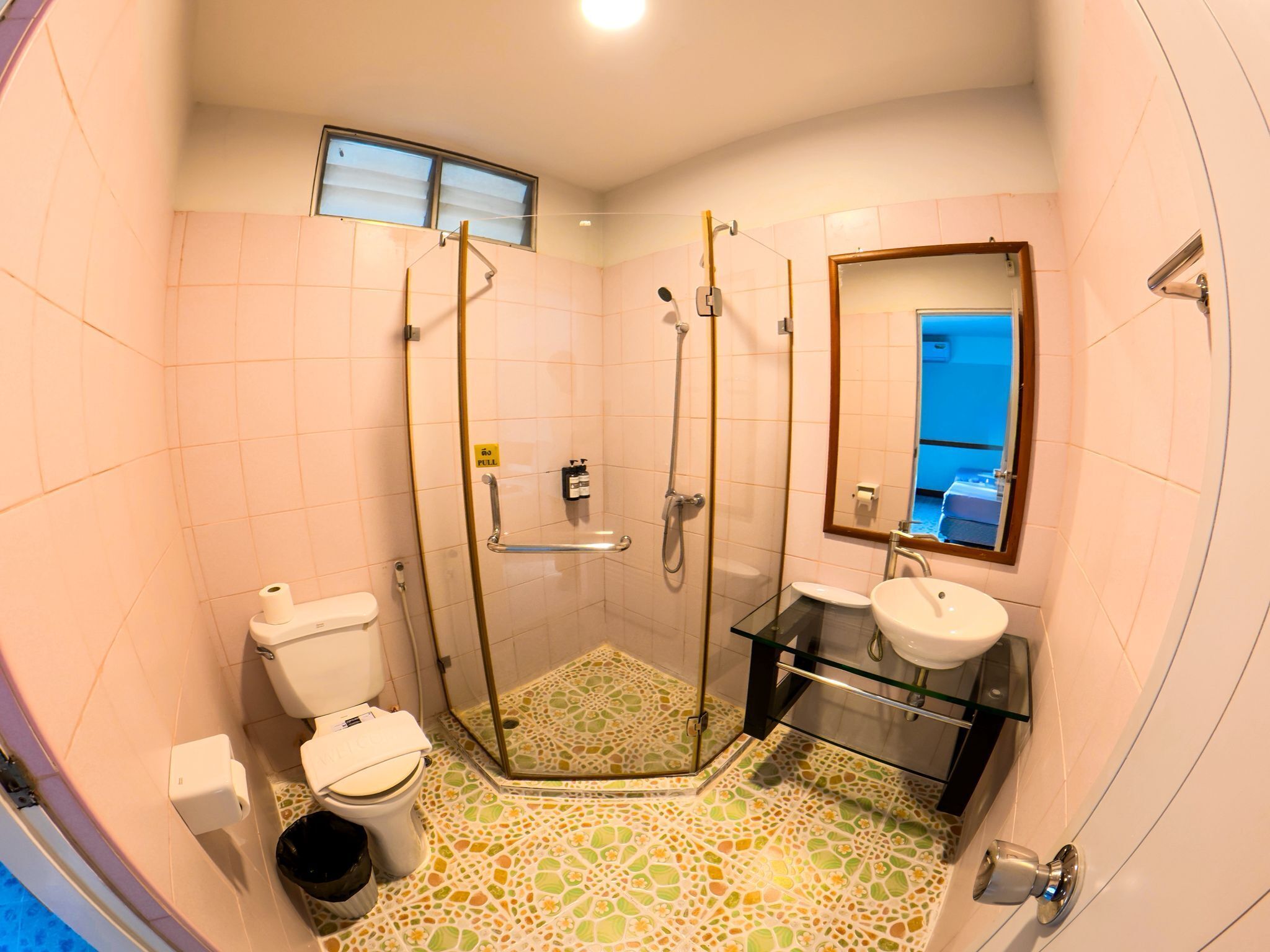 Ein Badezimmer mit Duschkabine aus Glas, Toilette, Waschbecken und Spiegel.