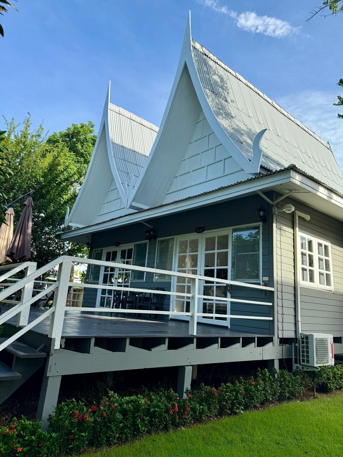 A two-story building with a steeply pitched roof and a balcony with white railings.