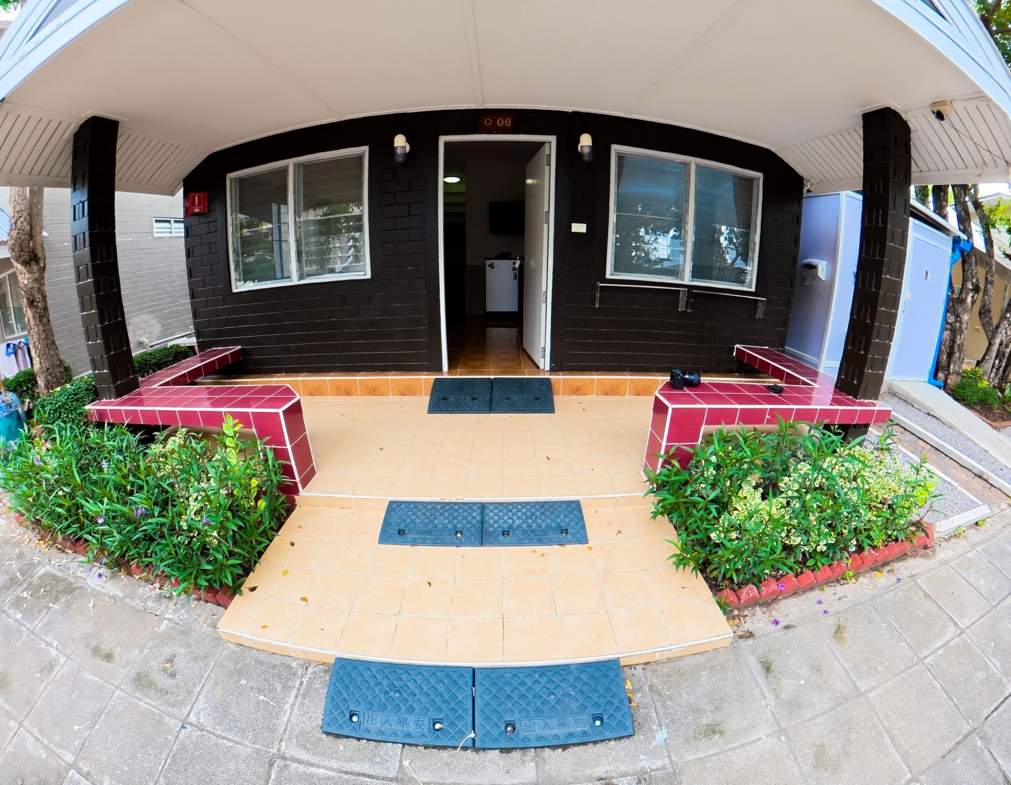A covered outdoor area with a tiled floor, benches, and a door leading inside.