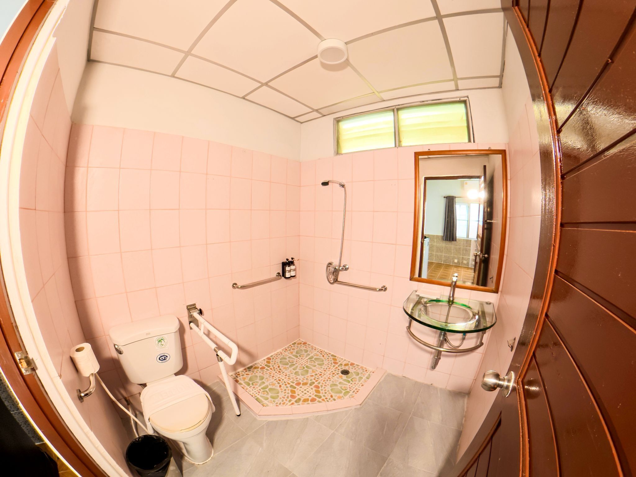 A bathroom with a toilet, a shower, a sink, and a mirror.