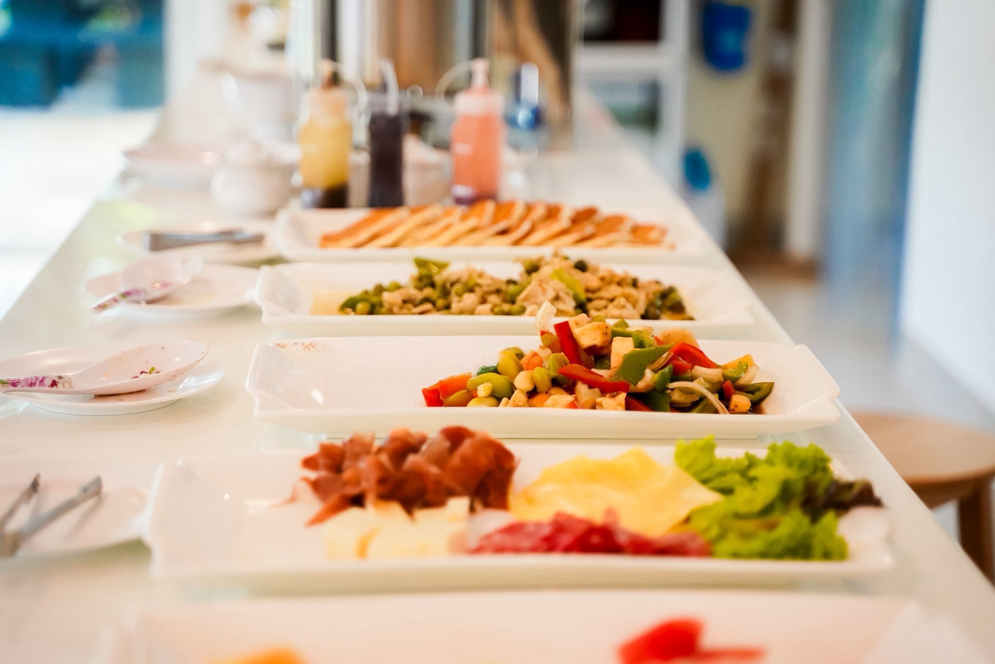 Une table de buffet proposant divers plats, notamment des salades, de la viande et des légumes.