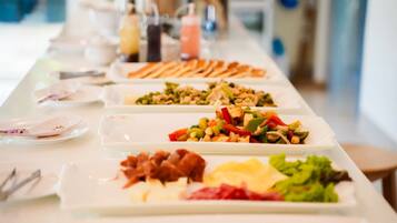 Une table de buffet proposant divers plats, notamment des salades, de la viande et des légumes.