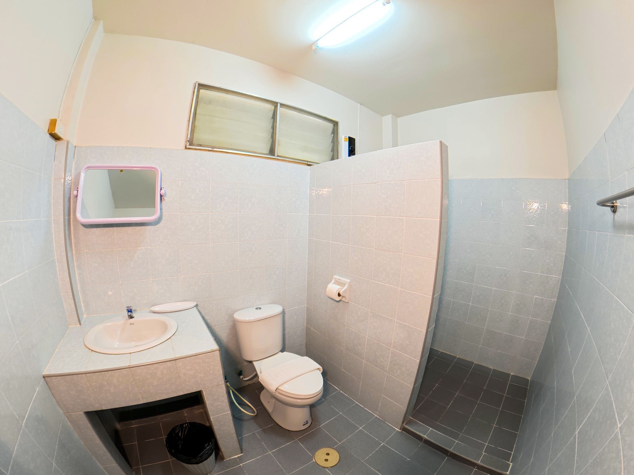 Baño pequeño y funcional con lavamanos, inodoro y cabina de ducha.