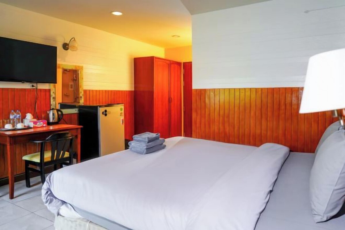 Una habitación de hotel con cama, escritorio, silla, televisor y armario.