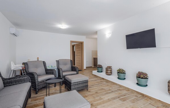 A modern living room with wicker furniture, a flat-screen TV, and potted plants. - Pet friendly home in Vrsi (Vrsi)