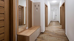Un pasillo con puertas de madera, un banco y suelo de baldosas.