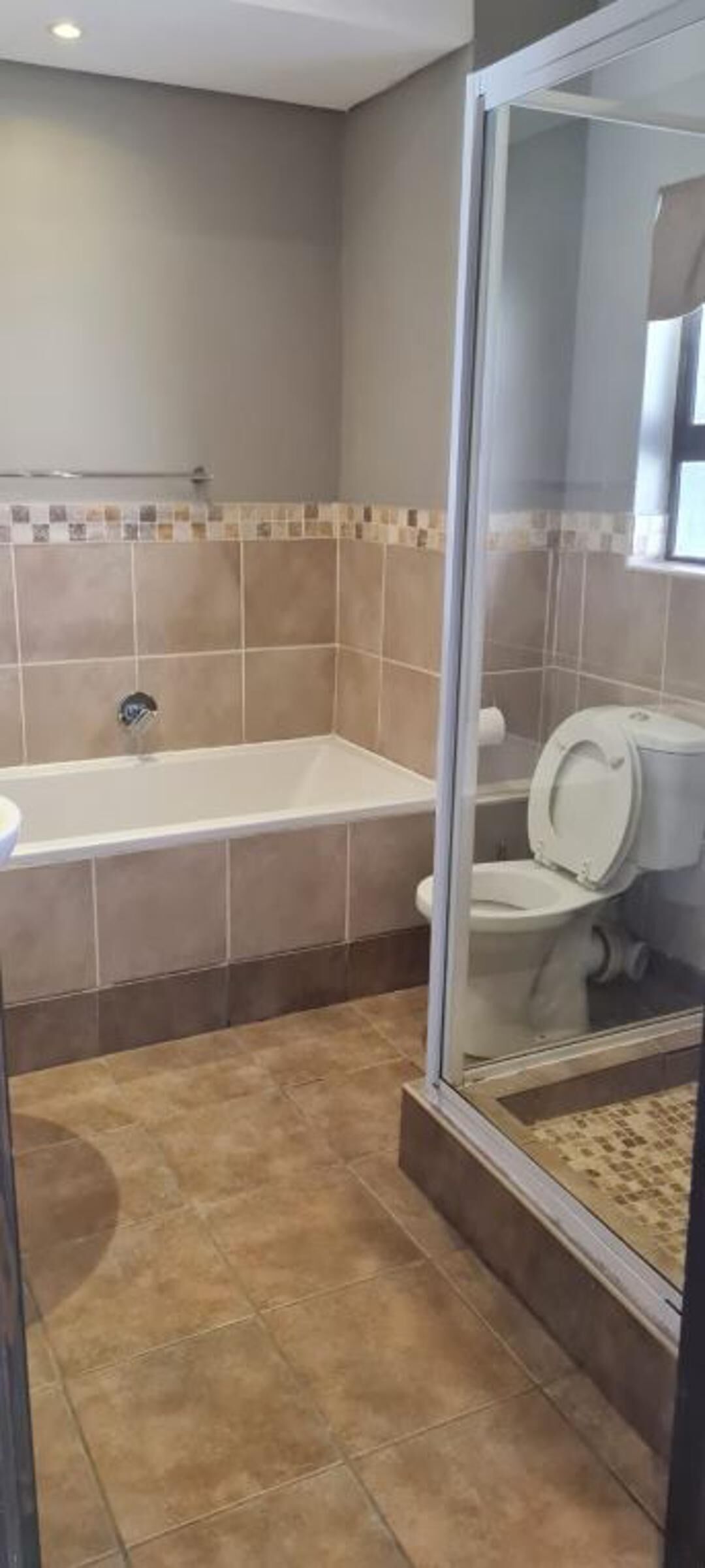 A bathroom with a bathtub, toilet, and shower area.