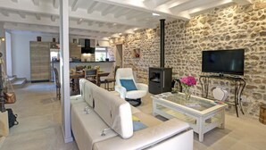 Een moderne woonkamer met een stenen muur, een open haard, een televisie en een bank.