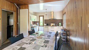 Una cocina moderna con paneles de madera, una isla central y un comedor con una mesa para cuatro.