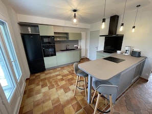 A modern kitchen with a central island, bar stools, and a dining area. - Spacieuse maison près des Châteaux de la Loire avec jardin clos, jeux pour enfants et visites de vignobles (Cheverny)