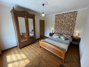 A bedroom with a wooden bed, a wardrobe, a patterned wall, and a ceiling fan. - Spacieuse maison près des Châteaux de la Loire avec jardin clos, jeux pour enfants et visites de vignobles (Cheverny)