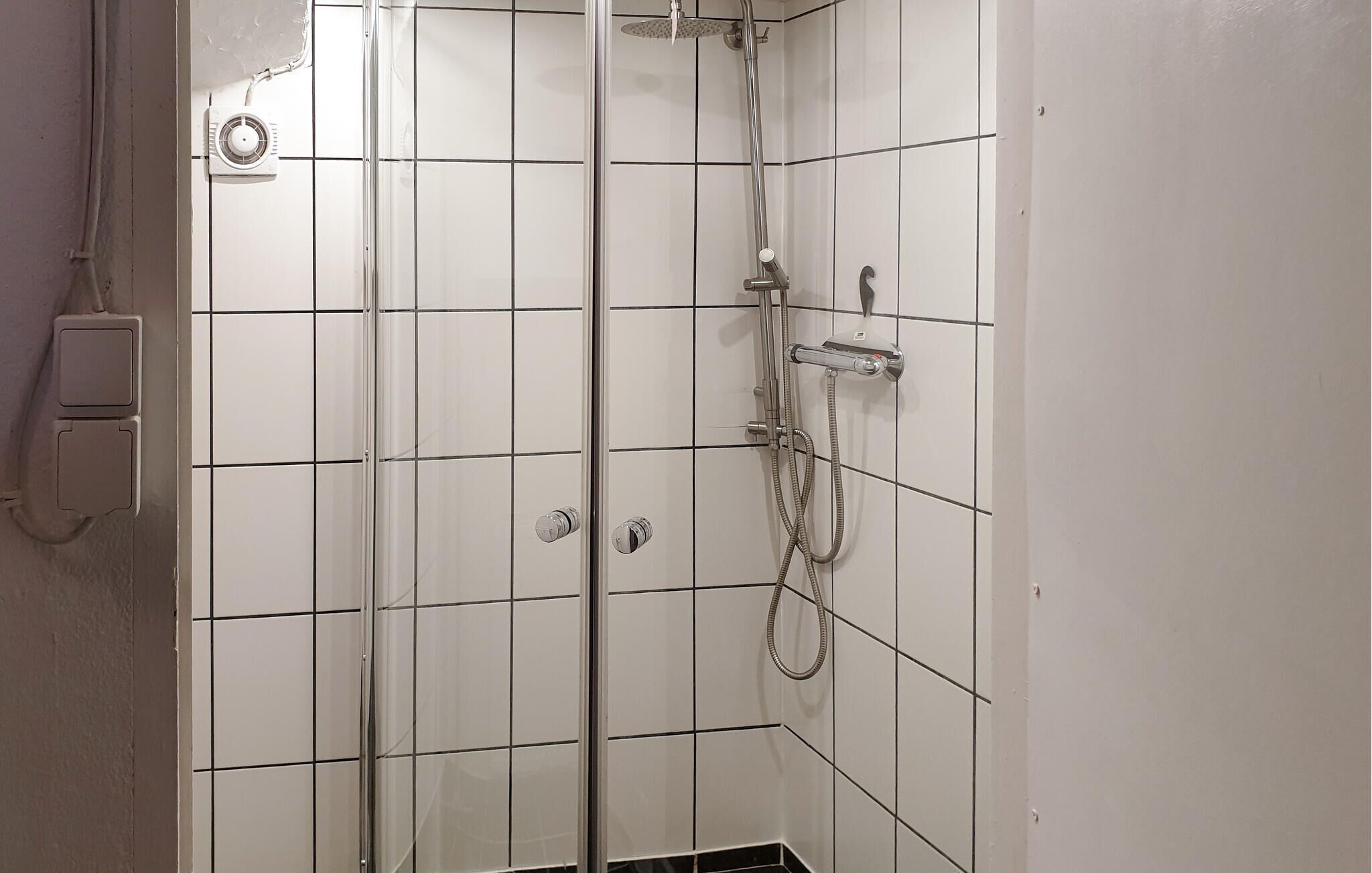 A shower with a handheld showerhead and a handheld hose.