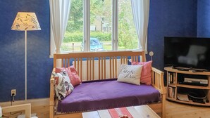 A cozy room with a wooden bench, a TV, and a window with curtains.