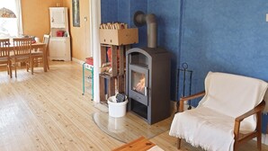 A cozy living room with a wood-burning stove, wooden furniture, and a blue accent wall.