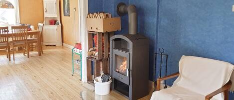 A cozy living room with a wood-burning stove, wooden furniture, and a blue accent wall.