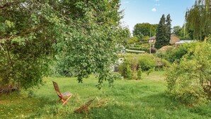 A grassy area with a wooden chair and a house in the background.