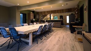 Een moderne keuken met houten kastjes, een groot eiland en een eetgedeelte met een lange tafel en stoelen.