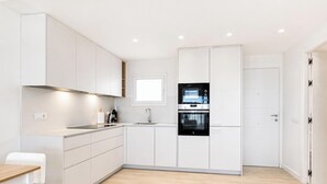 A modern kitchen with white cabinetry, a built-in oven, and a window above the sink.
